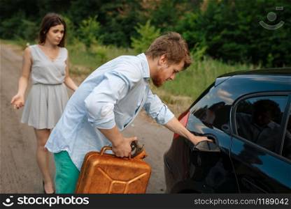 Young couple with a canister of gasoline, out of gas, car breakdown. Broken automobile or emergency accident with vehicle, trouble with punctured auto tire on highway. Couple with a canister of gasoline, out of gas