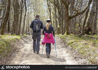 Young couple with a dog walking by hiking trail in the forest