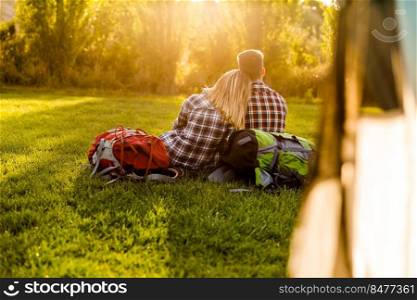 Young couple with backpacks sitting on the grass