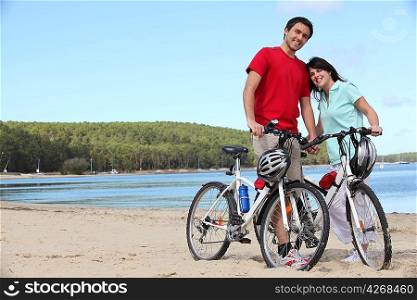 Young couple with bikes on a beach