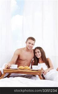 Young couple with breakfast in the bedroom