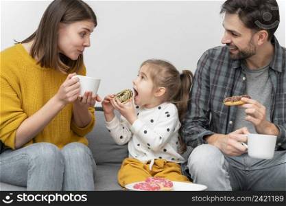 young couple with child eating donuts