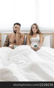 young couple with cup coffee sitting bed