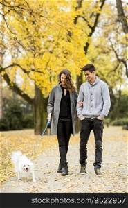 Young couple with dog in the autumn park