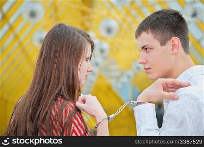 Young couple with handcuffs on footbridge