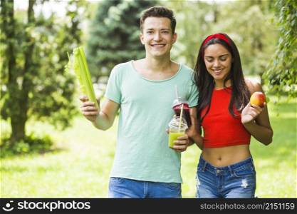 young couple with healthy food standing garden