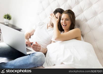 Young couple with laptop in the bed