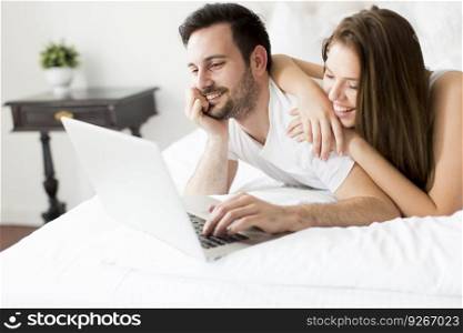 Young couple with laptop in the bed