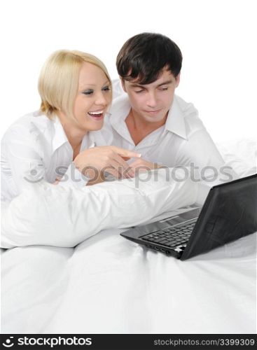 young couple with laptop lying on the bed. Isolated on white background
