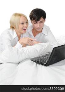 young couple with laptop lying on the bed. Isolated on white background