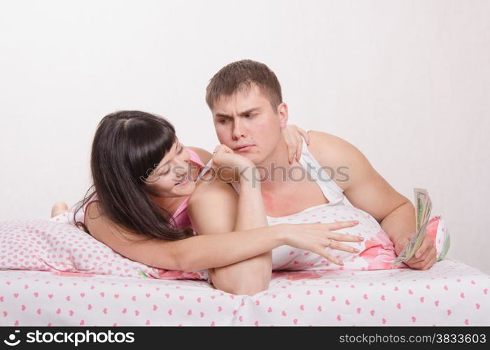 Young couple with money lying in bed