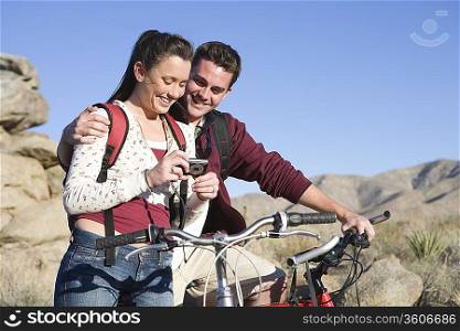 Young couple with mountain bikes stand looking at camera