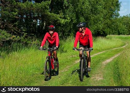 Young couple with mountine bike in spring nature on sunny day biking