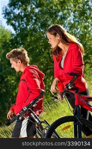 Young couple with mountine bike in spring nature on sunny day biking