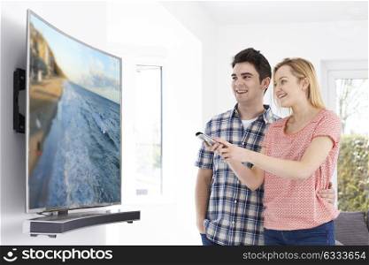 Young Couple With New Curved Screen Television At Home