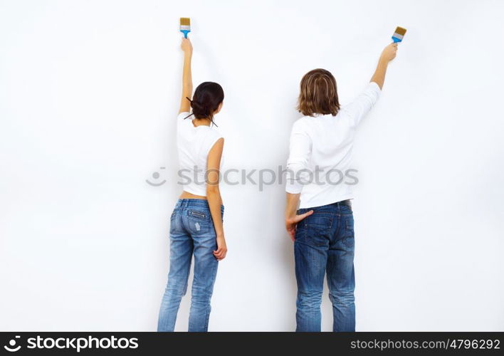 Young couple with paint brushes doing renovation together