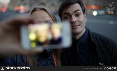 Young couple with phone making funny faces and taking pictures of themselfves