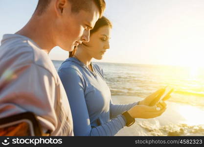 Young couple with smartphones outdoors. Two young people in sport wear with smartphones outdoors