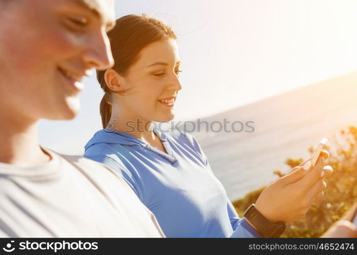 Young couple with smartphones outdoors. Two young people in sport wear with smartphones outdoors