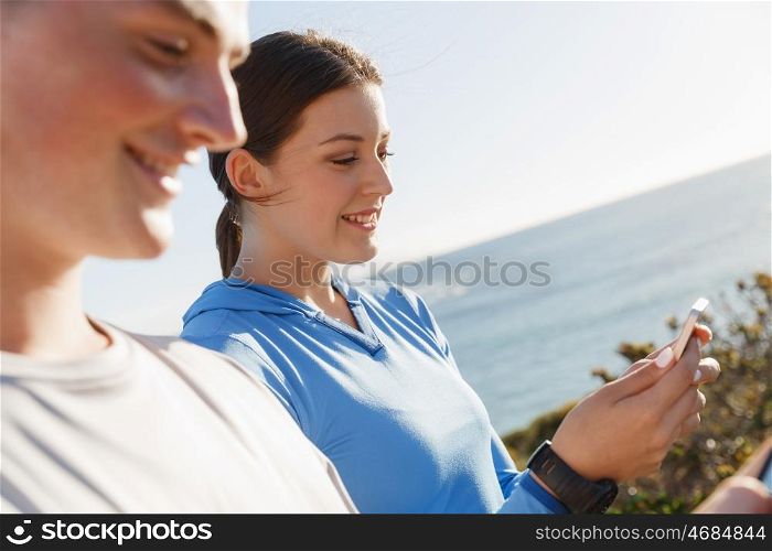 Young couple with smartphones outdoors. Two young people in sport wear with smartphones outdoors
