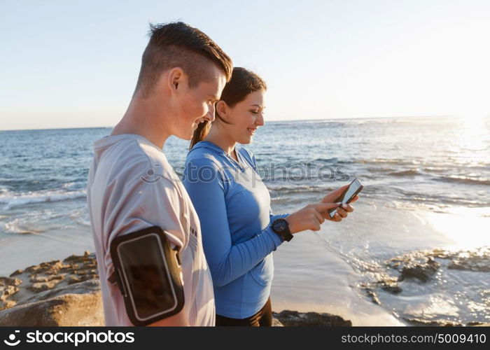 Young couple with smartphones outdoors. Two young people in sport wear with smartphones outdoors