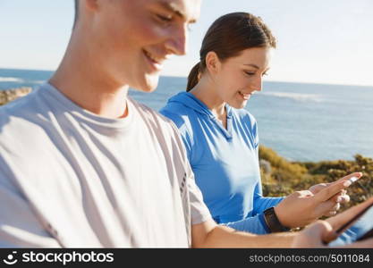 Young couple with smartphones outdoors. Two young people in sport wear with smartphones outdoors