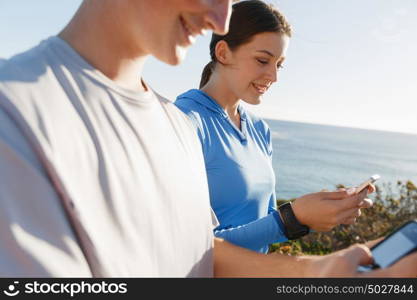 Young couple with smartphones outdoors. Two young people in sport wear with smartphones outdoors