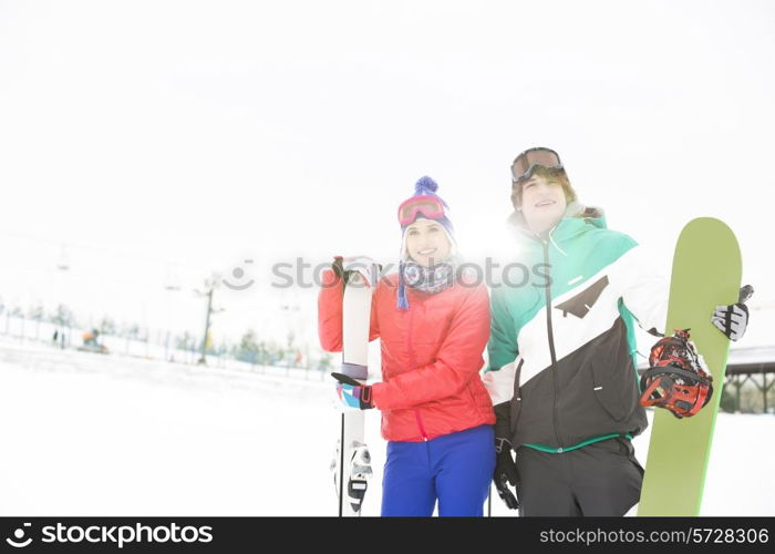 Young couple with snowboard and skis in snow