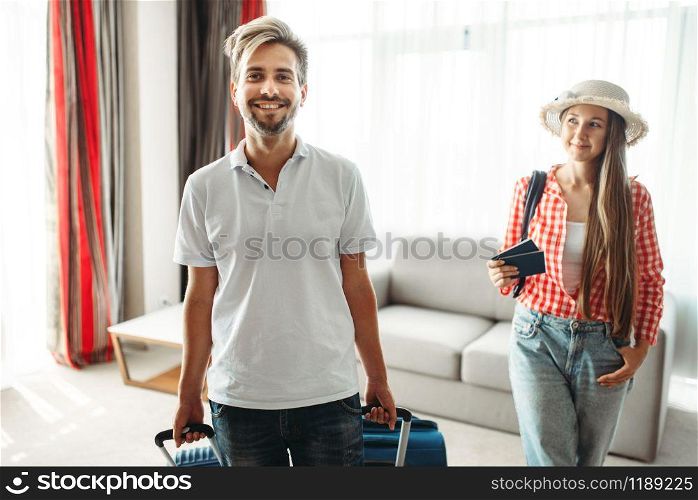 Young couple with suitcases sitting on the couch. Fees on journey concept. Luggage preparation. Travelling or tourism. Young couple with suitcases sitting on the couch