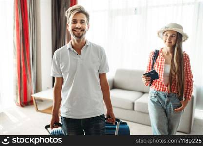 Young couple with suitcases sitting on the couch. Fees on journey concept. Luggage preparation. Travelling or tourism. Young couple with suitcases sitting on the couch