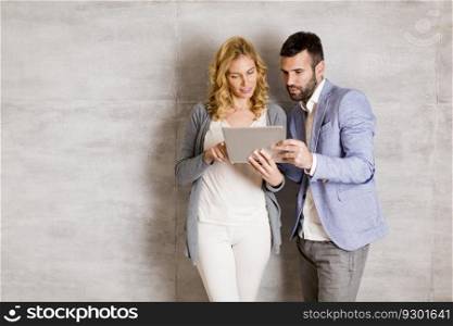 Young couple with tablet standing by the wall
