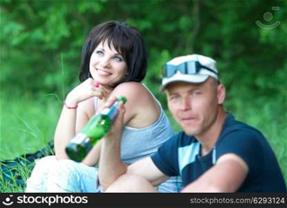 Young couple with the drinking man on the green field