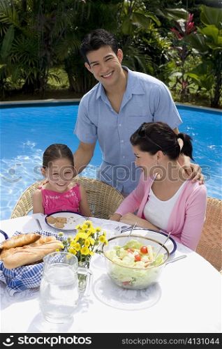 Young couple with their daughter at a breakfast table and smiling
