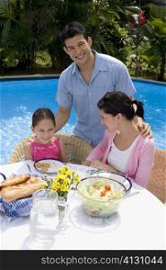 Young couple with their daughter at a breakfast table and smiling