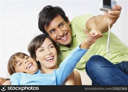 Young couple with their daughter taking a photograph of themselves