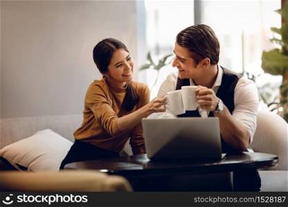 Young Couple Working Together on Computer Laptop in Cafe. Multiethnic Motivated Teamwork. Happy Business People