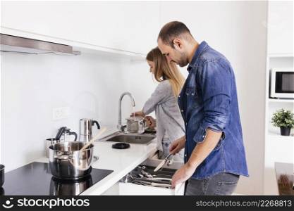 young couple working with utensils kitchen