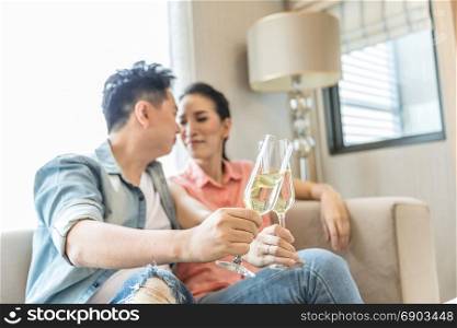 Young Couples celebrate together with wine in bedroom of contemporary house for modern lifestyle concept (Focus at glasses)