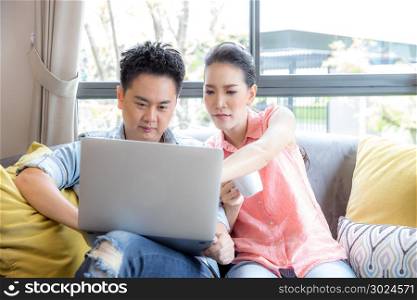 Young Couples using laptop tohether in living room of contemporary house for modern lifestyle concept