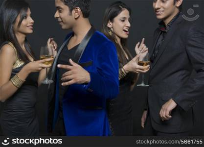 Young couples with drinks enjoying party against black background