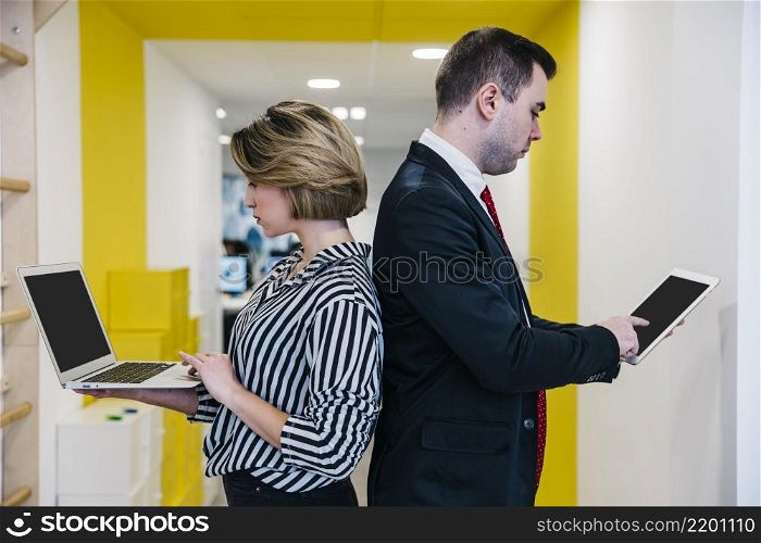 young coworkers using gadgets back back