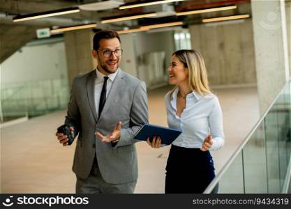 Young coworkers walking and talking along corridor in the modern office