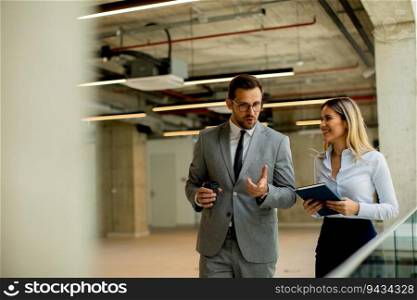 Young coworkers walking and talking along corridor in the modern office