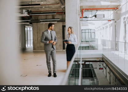 Young coworkers walking and talking along corridor in the modern office