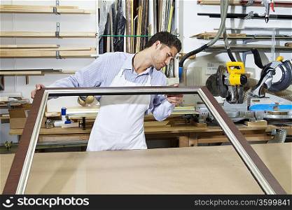 Young craftsman looking at picture frame