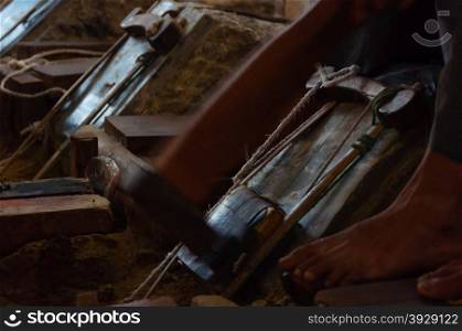Young craftsman punching gold in the traditional way to make leaf gold. in Mandalay, Myanmar