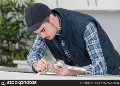 young craftsman repairing tap in a kitchen