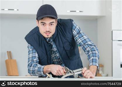 young craftsman repairing tap in a kitchen