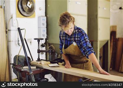 Young craftswoman checking wood in pipe organ workshop