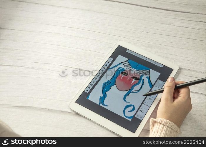 Young creative designer holding stylus pen drawing on screen of digital tablet on wooden desk with copy space, modern digital art top view space for text. Young creative designer holding stylus pen drawing on screen of digital tablet on wooden desk with copy space, modern digital art top view